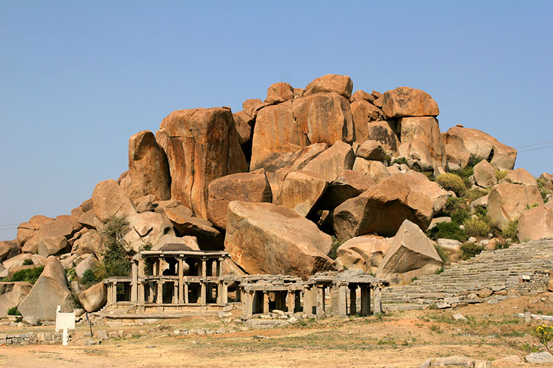 Colonnade structures at the far end of Hampi Bazaar mark the beginning of the trail to the top of Matanga Hill, set against the granite boulders that make up the surrounding landscape. 