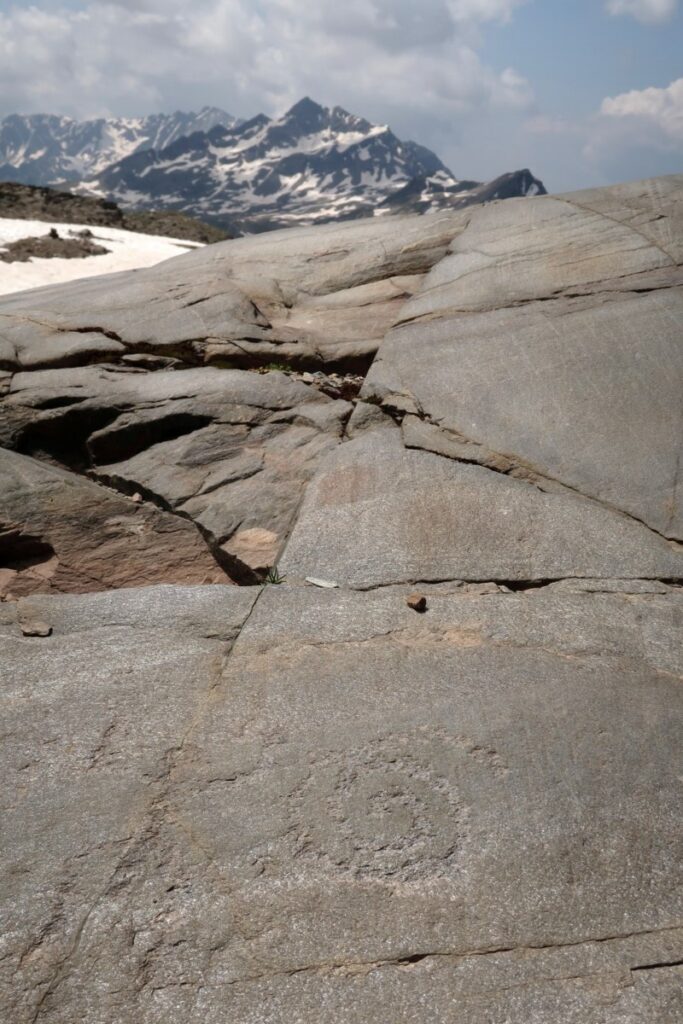 Petroglyphs depicting a human figure in a so-called praying position and a spiral design engraved on rock in Stelvio National Park, Lombardy, Italy