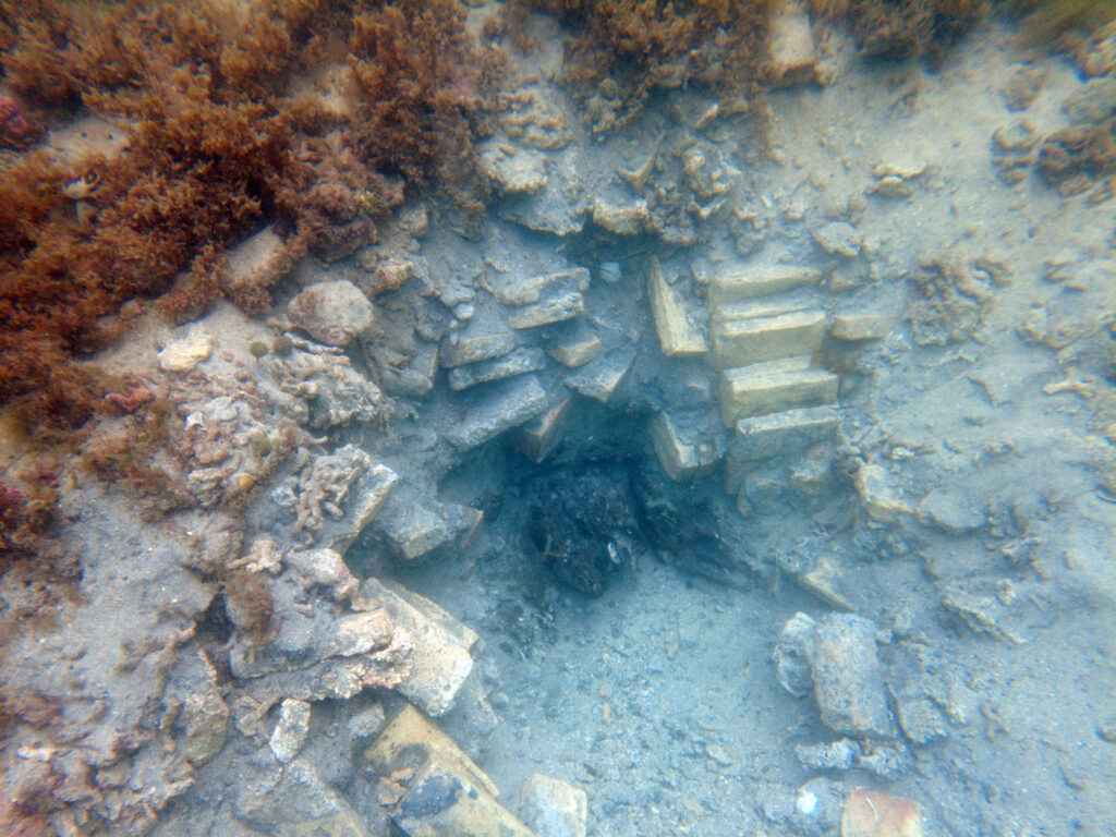 Excavated hole with visible bricks and wood from the shipwreck, Cahuita National Park, Costa Rica