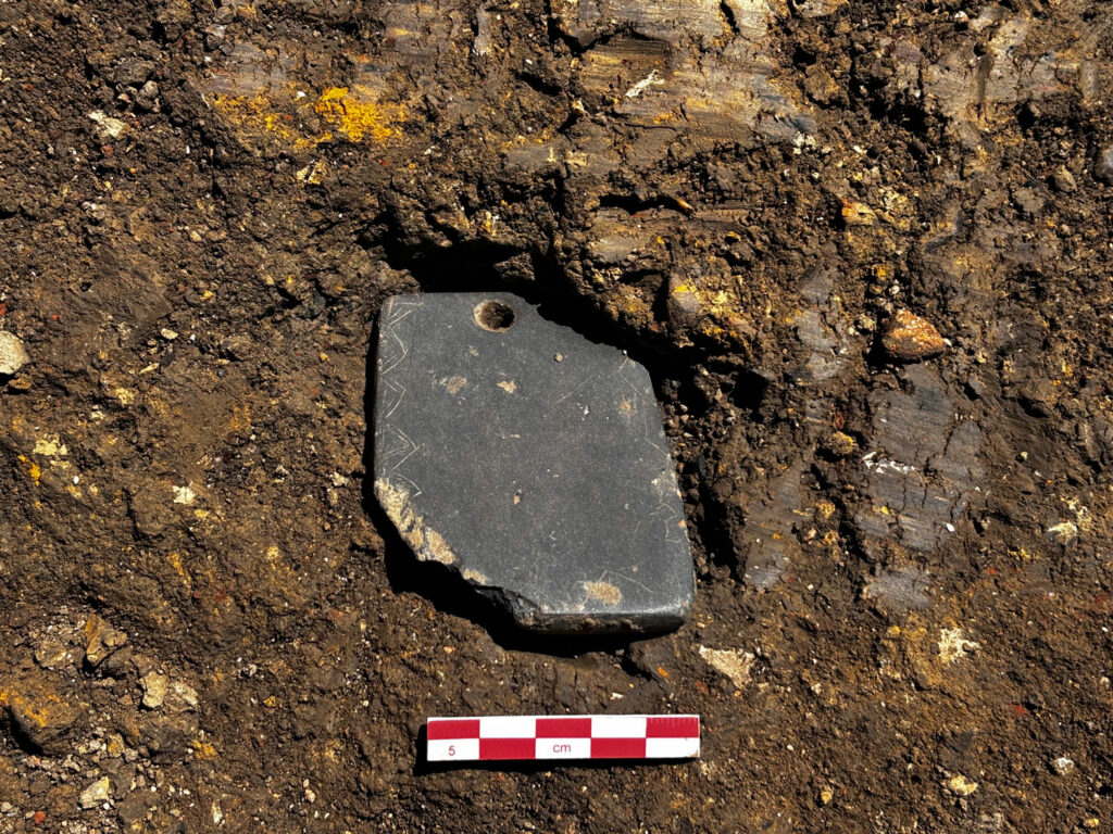 Slate pendant incised with geometric designs, shown in situ in Kuelap, Peru