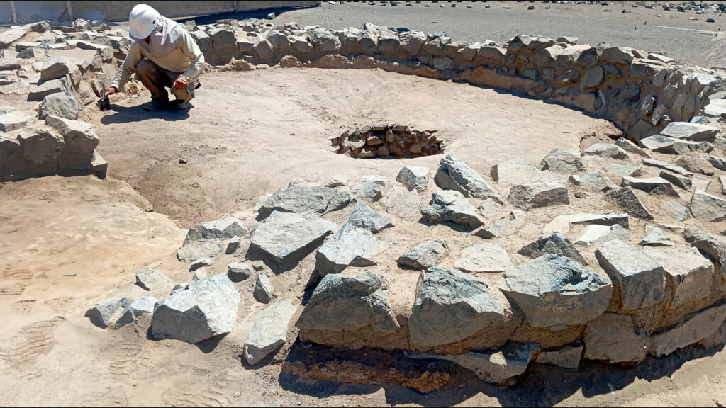 Archaeologist excavating inside a stone-ringed fire altar, Era de Pando, Peru