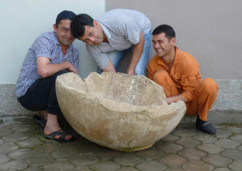 Men posing with ancient limestone basin