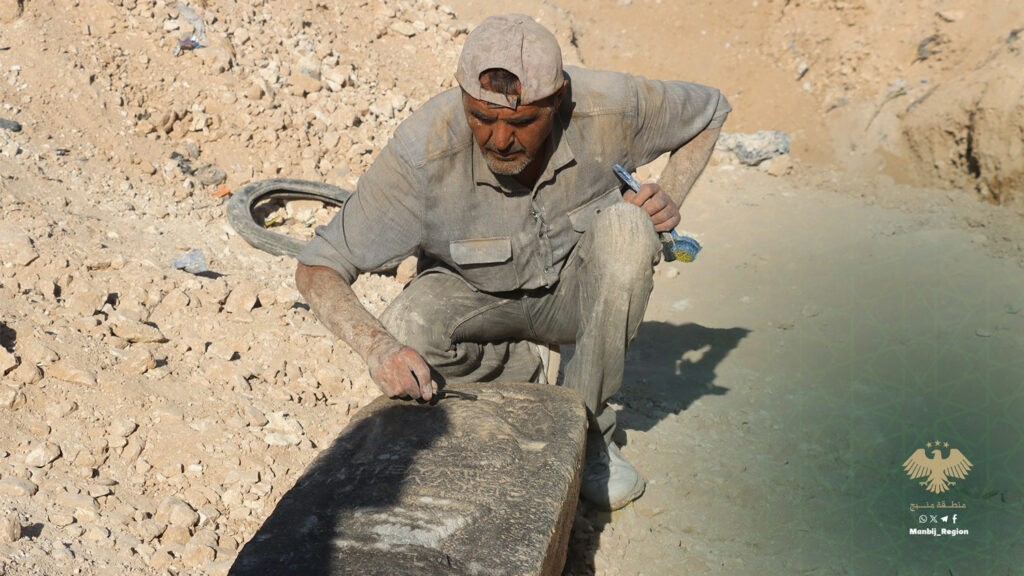 An archaeologist examines the stele unearthed in Manbij, Syria.