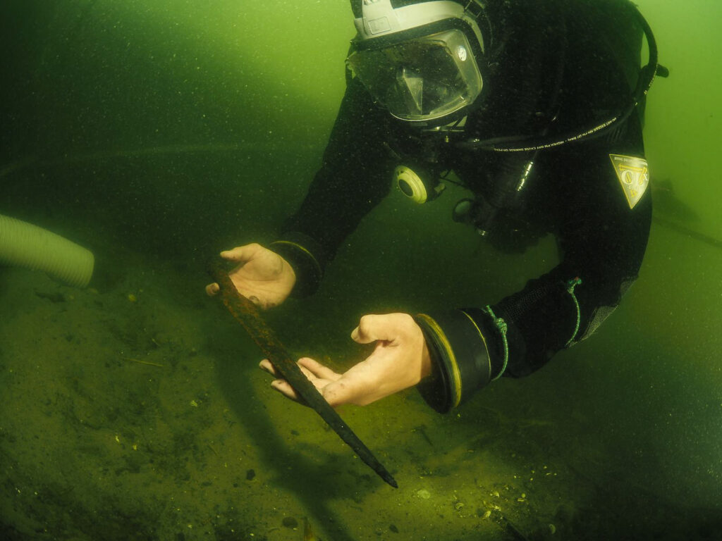 An archaeologist recovers a spear in Lake Lednica, Poland.