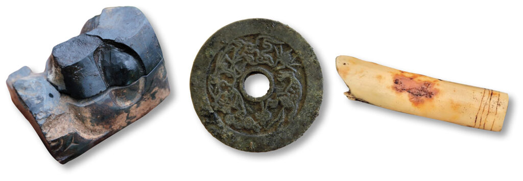 Carved argillite (left), amulet (center), and straw fragment (right)
