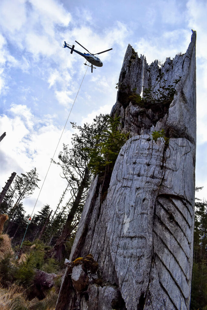 A helicopter removes fallen debris at SGang Gwaay