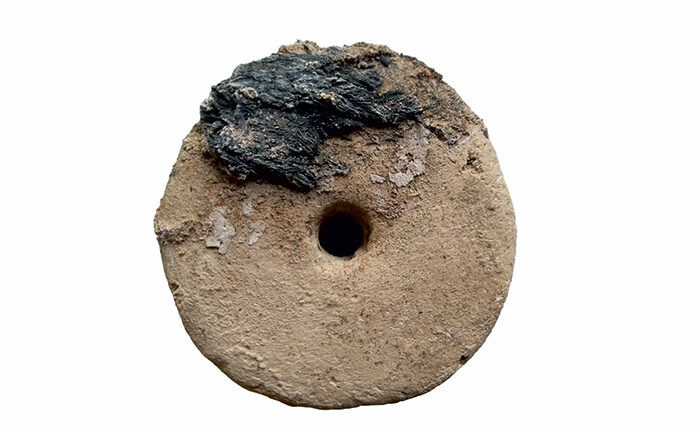 Loom weight encrusted with charred esparto grass