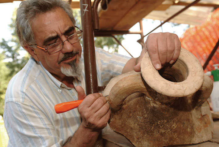 Archaeologist Jos&eacute; Remesal cleans dust from an amphora handle stamp