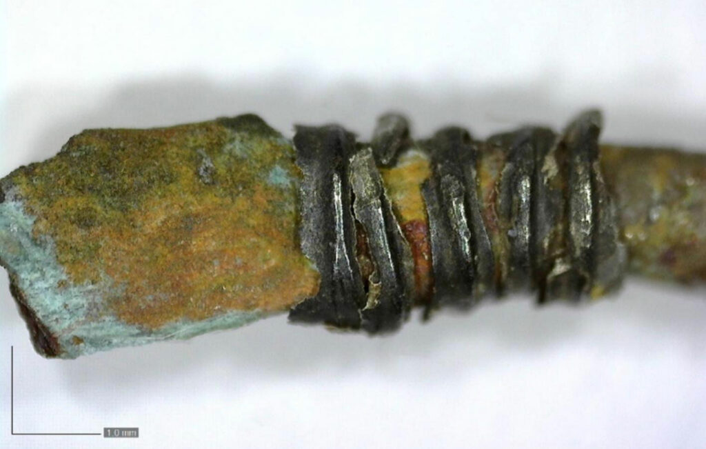 Magnified view of silver wire wrapped around the bronze brooch