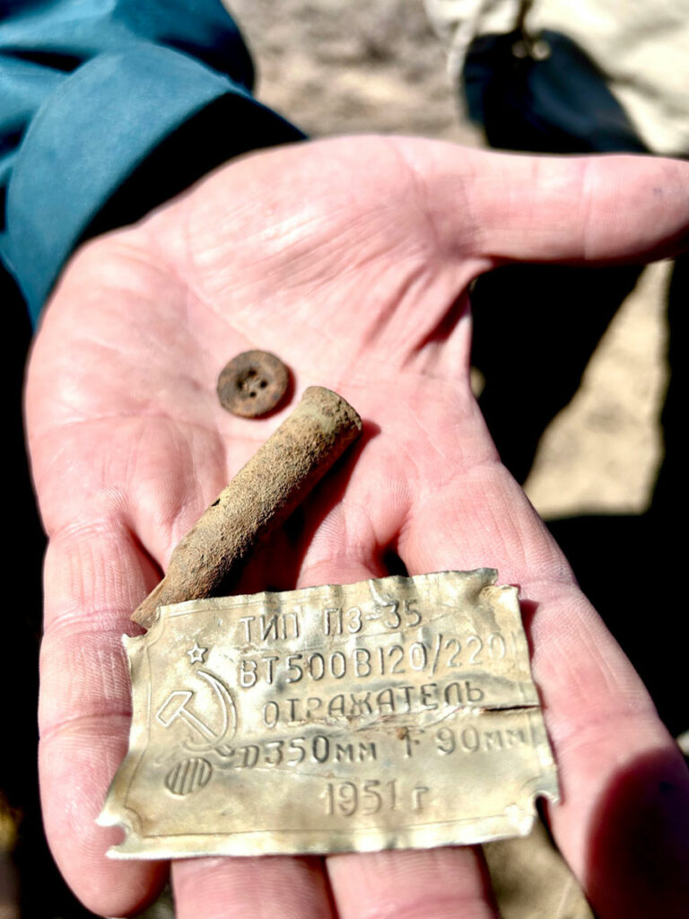 Artifacts recovered from a Soviet gulag in Kazakhstan include a uniform button, a bullet casing, and a label dating to 1951 from a lamp used to illuminate the fenced perimeter.