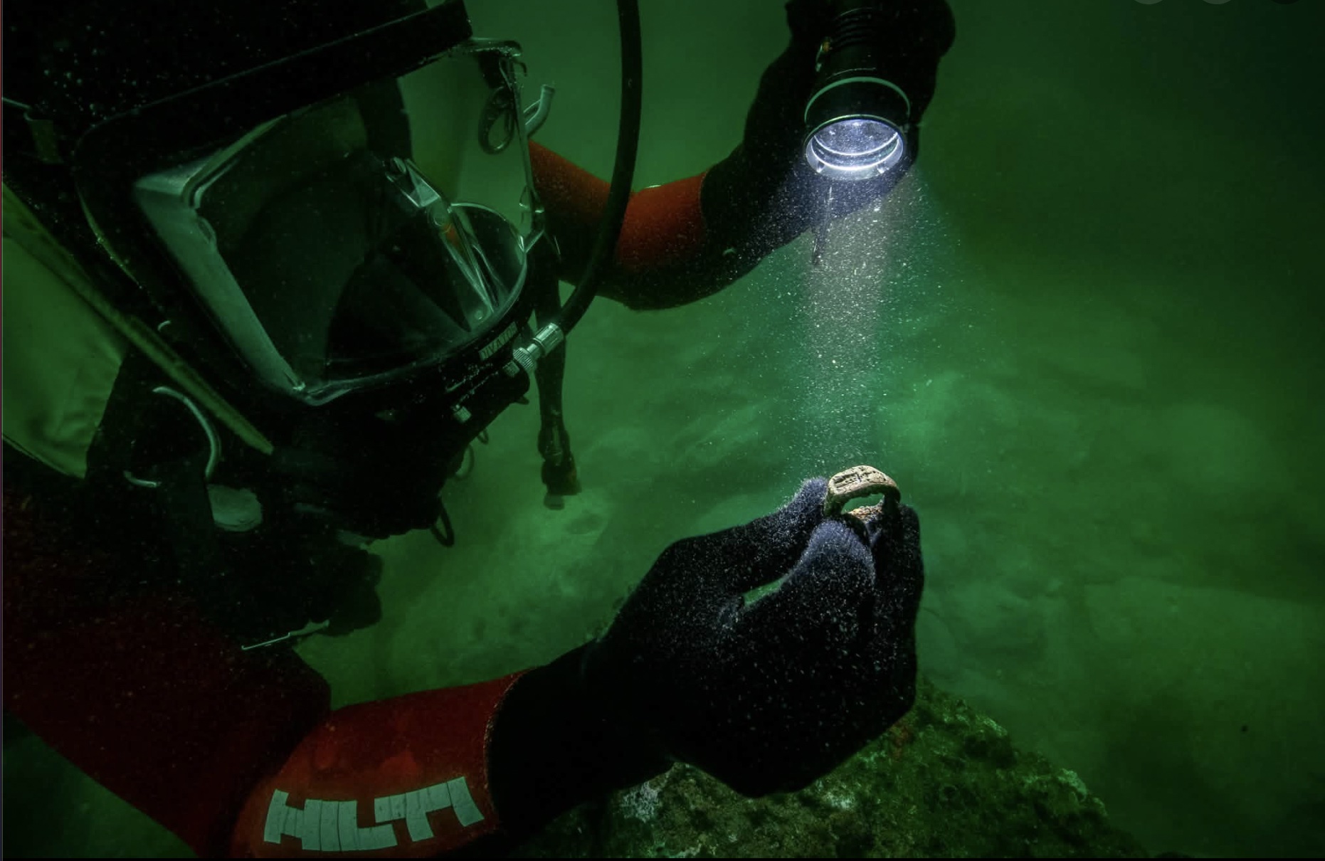 An underwater archaeologist looks at a bronze ring recovered from the harbor of Alexandria, Egypt.